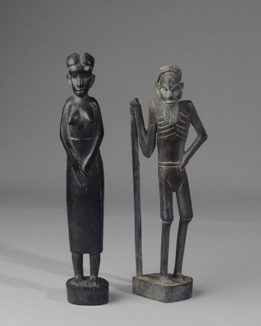 Pair Vintage African Ebony Wood Carvings: Elongated figures of a man and a woman, carved of fine-grained black wood, probably ebony. Male is initialed "YM" to base. Female is 12 3/4" in height.