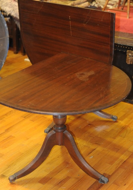 Early Duncan Phyfe Style Dining Table: Probably mahogany, two tilt top sections, each with base terminating in three curvilinear reeded legs with brass claw feet over casters, string inlay to top. H: approx. 29".