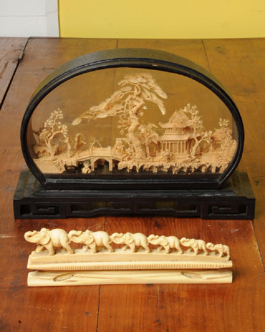 Chinese Carved Cork Scene, more: Vintage intricate scene of pagodas and trees with birds carved of cork in glass fronted carved wood display stand. Presented with carved bone or resin parade of elephants. Cork carving approx. 12 1/2"