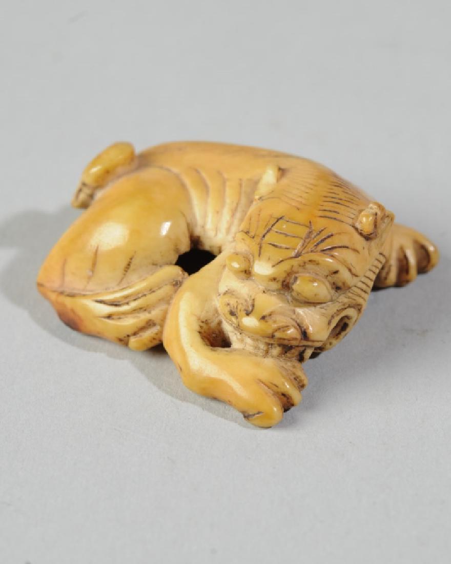 Edo / Meiji Foo Dog Japanese Netsuke: Good warm natural patina. Carved wide divided channel on underside with feature that seems designed for wrapping cord; possibly some kind of buckle or slide? Approx 1 1/4" x 1 1/4". From the estate of