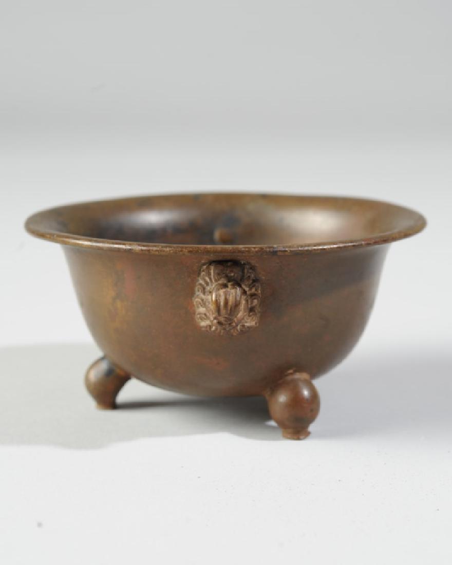Antique Chinese Bronze Tripod Censer: Small round bowl censer with everted rim standing on three short curved feet, with well-formed mask handles. Impressed Xuande mark to base. Approx. 4" diameter, 2" height. From the estate of Curtis E.