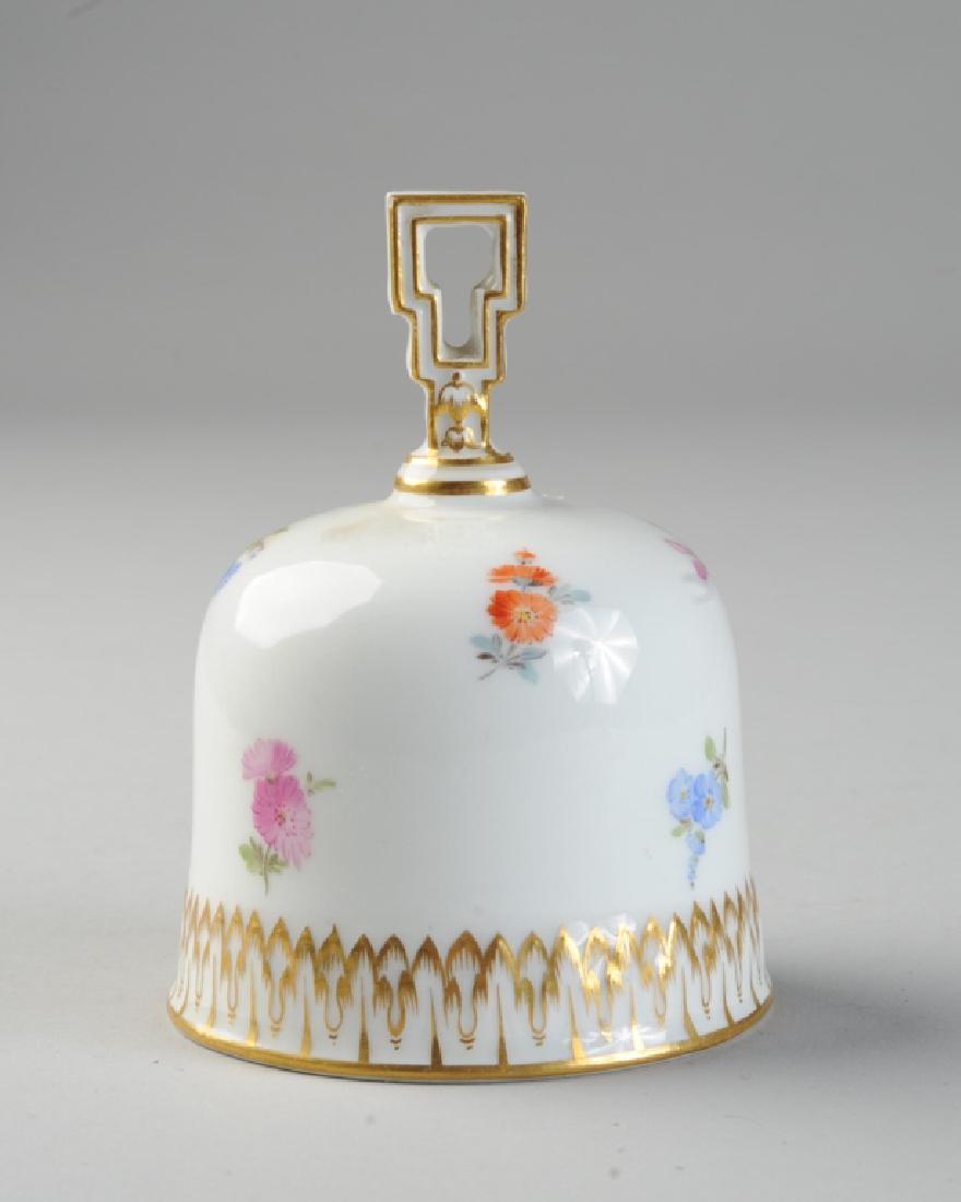 Meissen Porcelain Bell: 19th Century bell with scattered blossoms and molded gilt border. Crossed swords mark in blue to interior. Approx.. 4" in height.