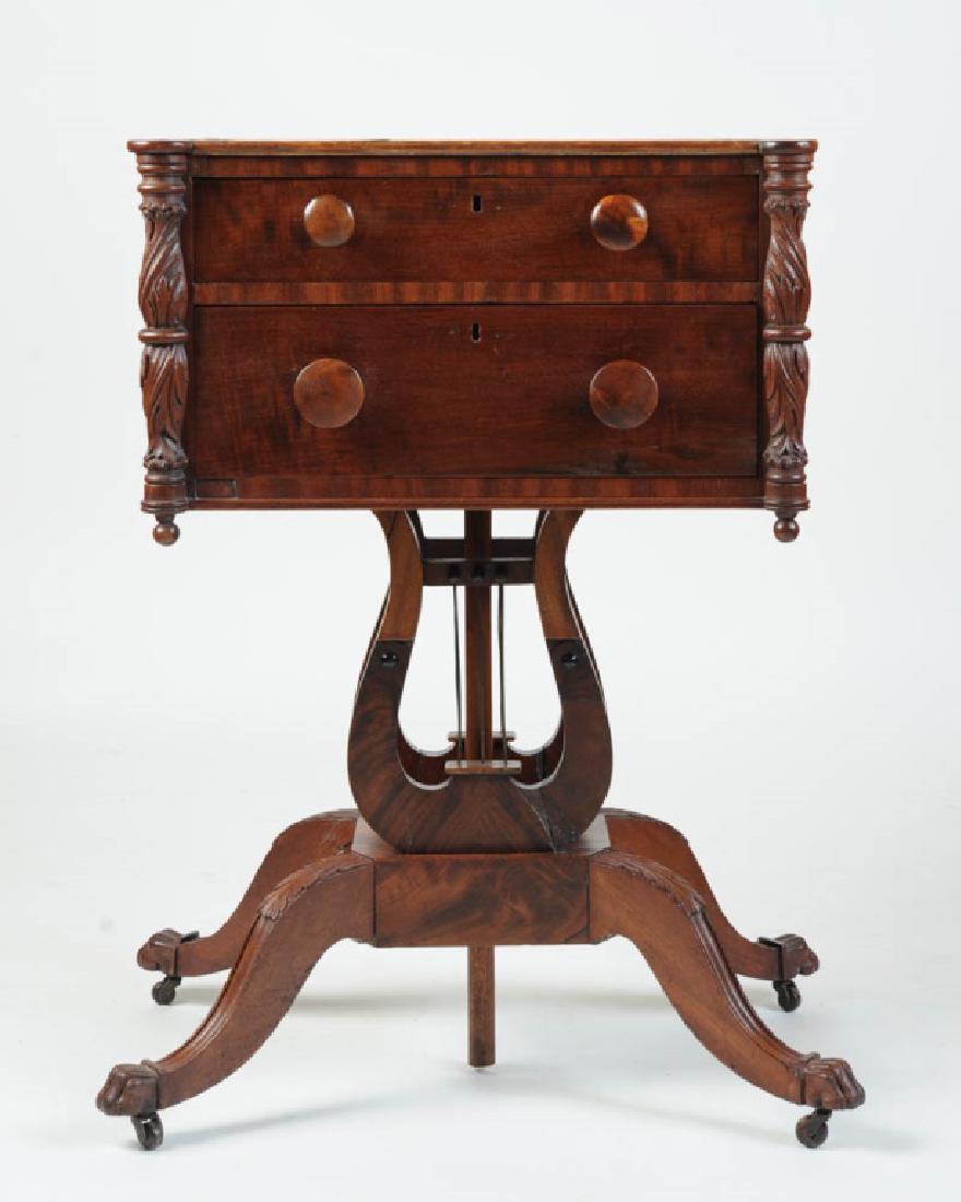 19th C. Duncan Phyfe Style Lyre Based Work Table: Mahogany table with two drawers with wooden pulls (probably replacements) flanked by carved acanthus urns over lyre base with four carved legs with claw feet and casters, secondary woods Tulip Poplar