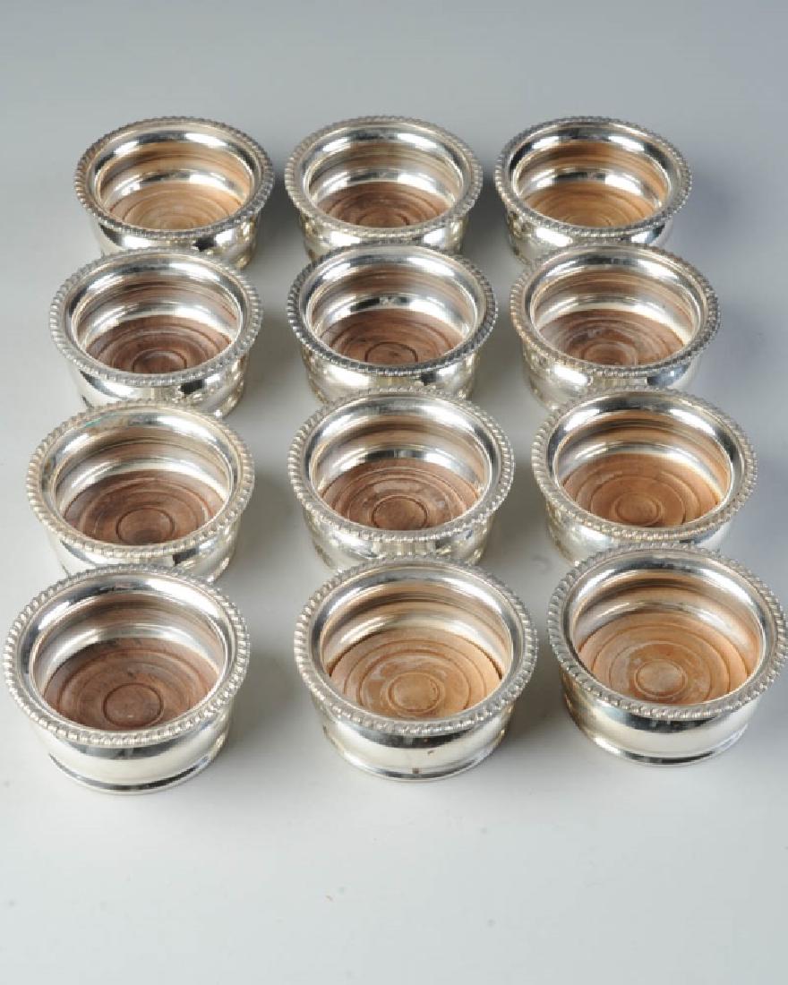 12 Small Silverplate Wine Coasters: With turned wooden inserts, unmarked. H: approx. 1 1/2". Dia: approx. 3 1/2". Provenance: The collection of Ambassador and Mrs. Alexander Weddell of Virginia House Museum, Richmond, Virginia.
