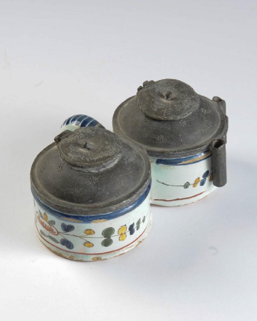 18th C. Delft Polychrome Double Inkwell: With floral decoration in blue, rust, gold and green, and with lead covers and quill holders, the lead impressed with small stars. Surface wear and minor losses, no cracks or repairs. One lid detached