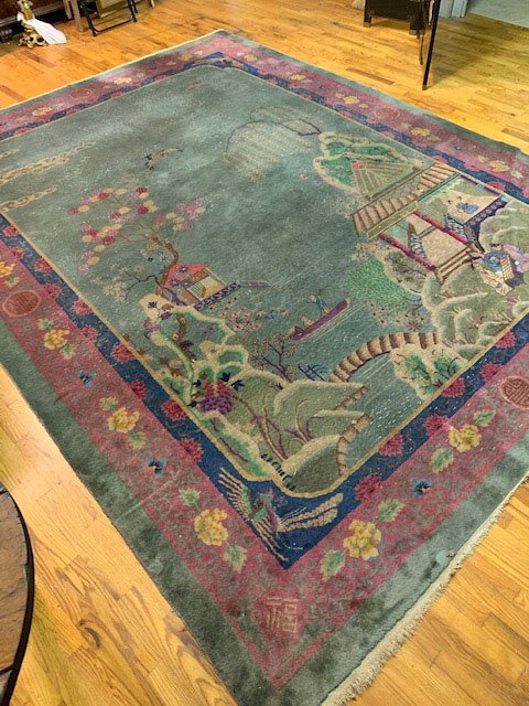 Semi-Antique Chinese Art Deco Peking Rug: Peking rug has celadon ground with a scene of figures near a lake with willow tree, pagodas and boats. Mauve border with flowers and with shou (longevity) characters. Woven chop type mark may be a sig