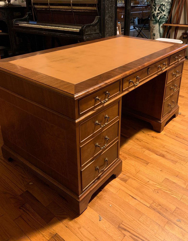 Kittinger Leather Top Writing Desk: Leather top, nine dovetailed drawers with Kittinger label to upper left drawer, brass pulls, no key and untested lock. H: approx. 30". W: approx. 59". D: approx. 32".