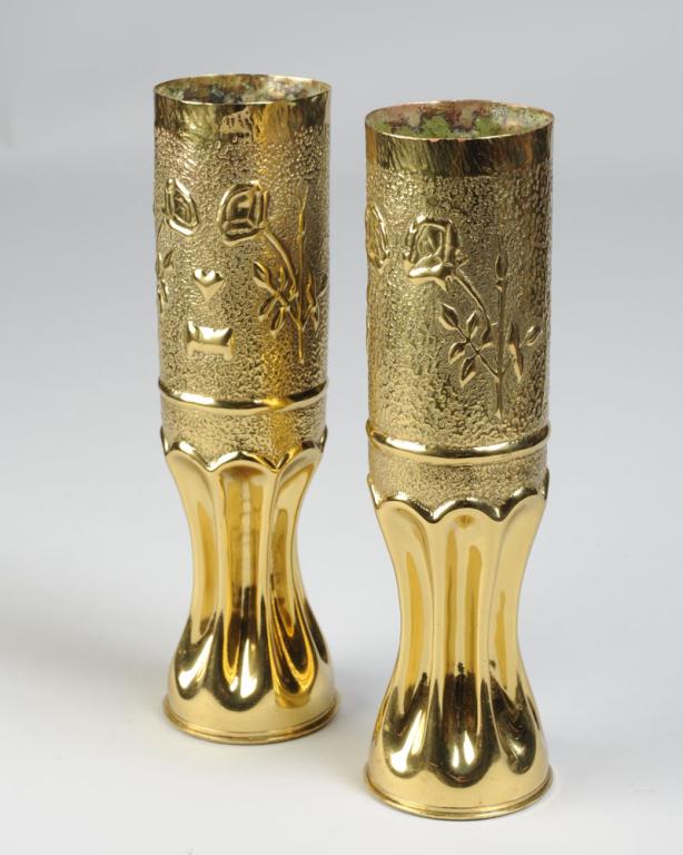 Two WWI Trench Art Shell Vases: Near pair both with repousse floral motifs, one with heart, both marked to underside (one marked USA.) H: approx. 11 3/4".