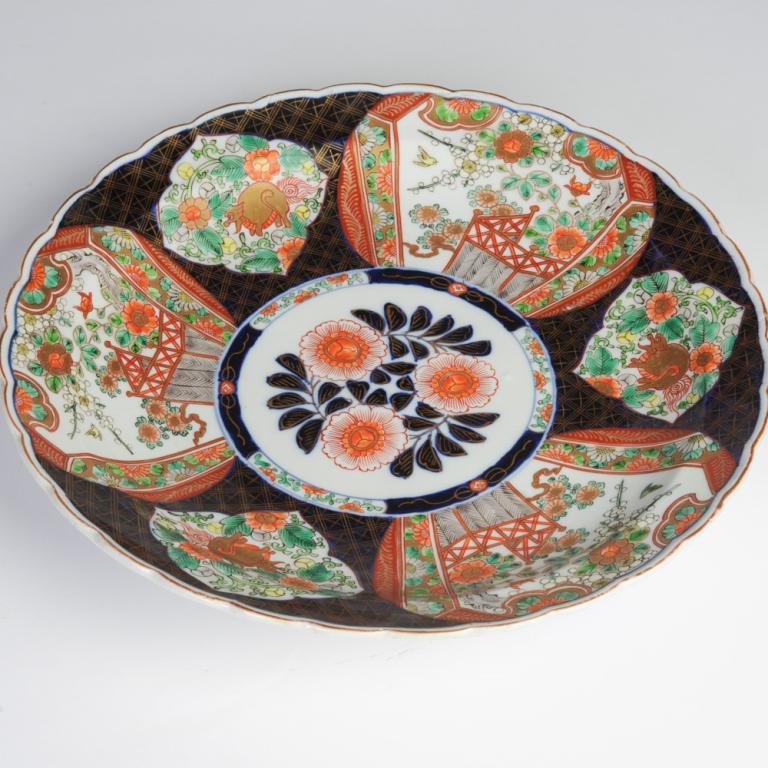 Meiji Arita Imari Charger: 19th C. Japanese Imari charger with scalloped rim, dark blue ground with gilt diaper pattern and reserves with squirrel (?) and roses along a fence, the center with three red blossoms and deep blue an