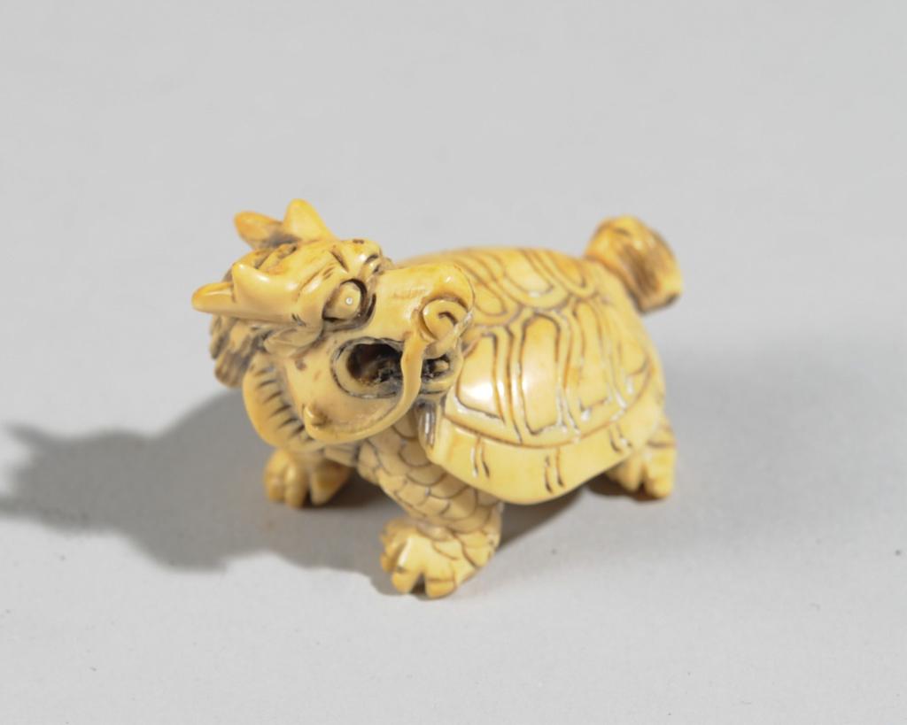 Chinese Carved Bone Toggle Longgue: In the form of the mythical beast the Longgue, part dragon and part turtle. Two characters carved to underside. Approx. 1 3/4" head to tail.