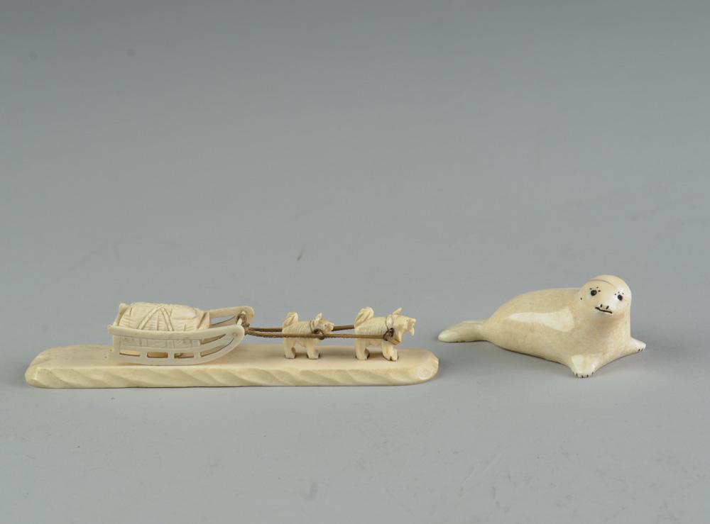 Two Alaska Inuit Carvings: Small carved bone seal signed "Anthony Ozenna". Dog sled with two-dog team, (human figure missing,) is unsigned. Dog sled carving approx. 5 1/2" in length.