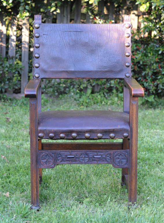 Gothic Revival Armchair: 19th C. oak armchair with square leather back and seat, the front stretcher with shallow relief carved flower heads. Ball feet possibly later addition to add height. Approx. 44 1/2" height at back of 