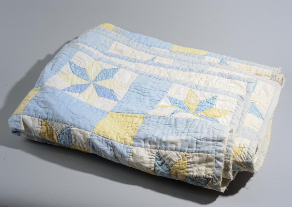 Vintage Star Quilt: Hand sewn quilt with a repeating star pattern in blue, yellow and white cotton squares. Early to mid 20th C. Some wear, fraying of edge, minor stains. Approx. 80" x 58".