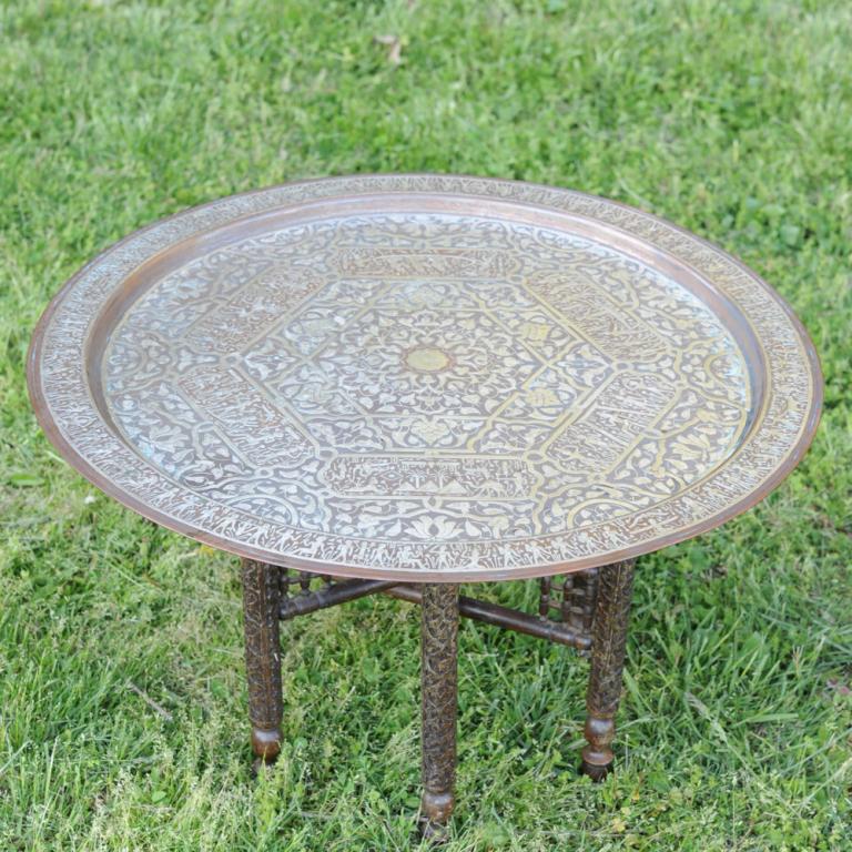 Egyptian Revival Cairoware Tray Table: Heavy copper Damascene tray with profuse silver inlay showing figures in the style of ancient Egypt and lotus leaf arabesques, on a folding carved wooden six-legged stand. Early to mid 20th C. Approx.