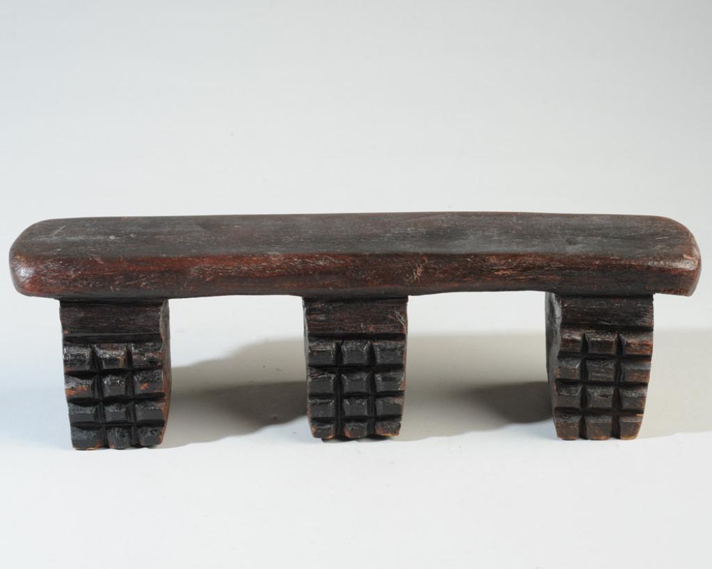 African Zulu Headrest: With three chip carved legs. Approx. 15" L x 4 1/4" H x 3 1/4"W. Provenance: Estate of Thomas McNemar, (1931-2019.) McNemar lived and collected throughout Central and West Africa in the 1960s and 70s.