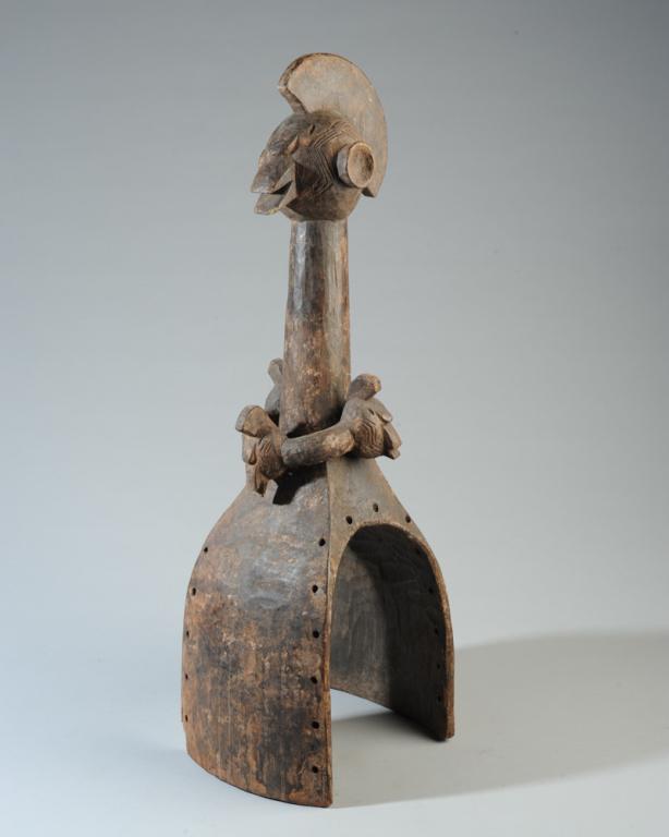 Waja Shoulder Mask: Carved wooden shoulder or yolk mask, Waja people, Nigeria. Crested head, protruding ears, beak-like mouth. With necklace bearing three similar heads. Tribal repair/reinforcement with wire. Approx. 25"