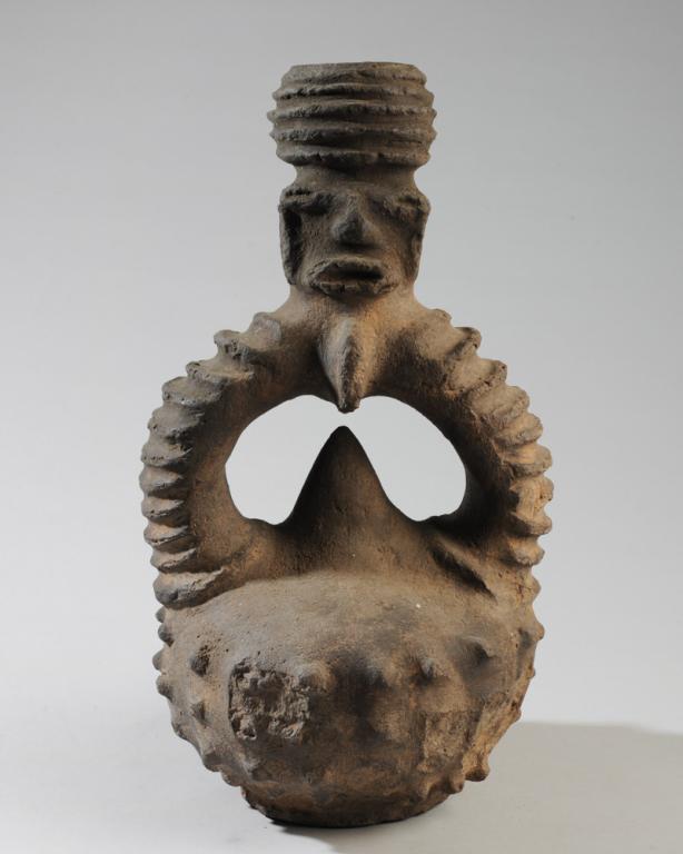 Azande Janiform Medicine Pot: Figural stirrup form pot with head as spout, two chambers leading to pointed, spherical body, Zande people, DR Congo. H: approx. 16 1/4". Provenance: Estate of Thomas McNemar, (1931-2019.) McNemar liv