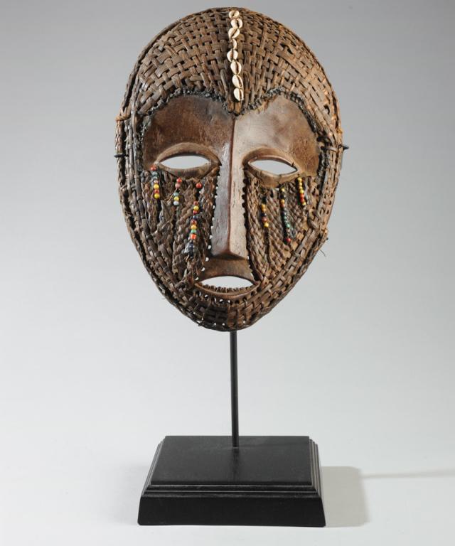 Lega Mask: Carved wood, woven rattan, beads, cowrie shells. On gallery stand. Approx. 15" x 10". Provenance: Estate of Thomas McNemar, (1931-2019.) McNemar lived and collected throughout Central and West Africa 