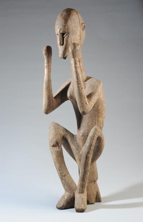 Seated Dogon Statue / Figure, Mali: Serene figure, seated, with curved back, elbows bent, hands raised on each side of face. Encrusted surface. Dogon people, Mali. Approx. 28" in height. Provenance: Estate of Thomas McNemar, (1931-2019.