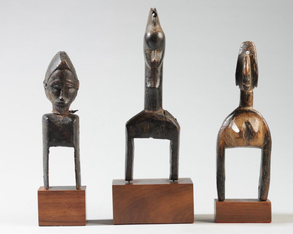 Three African Figural Heddle Pulleys: Carved wood. Probably Ivory Coast. Split with old repair to tallest figure at shoulder. Each mounted to gallery stand. Tallest approx. 10 1/2" H (including stand.) Provenance: Estate of Thomas McNemar