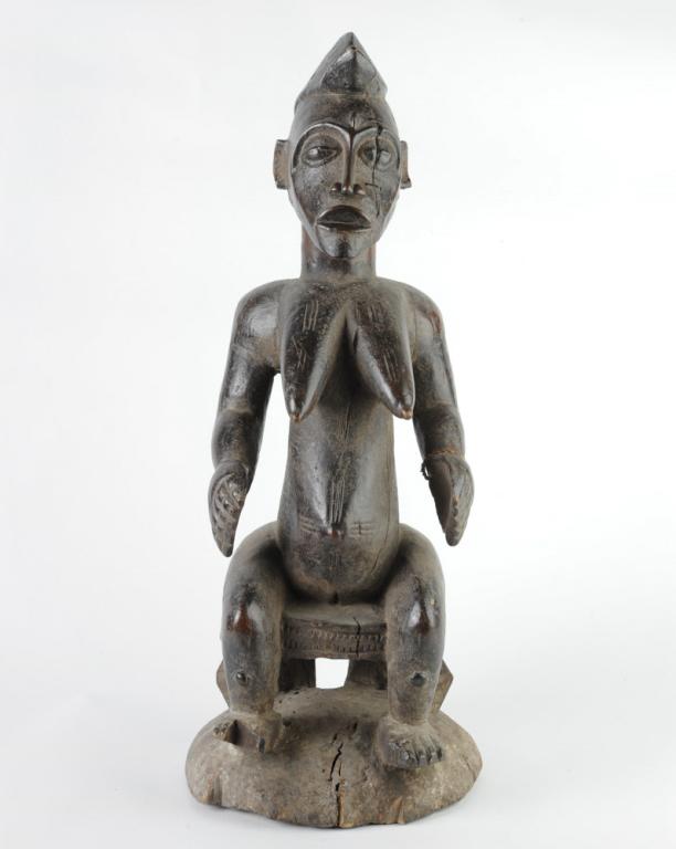 Senufo Sculpture Seated Female Figure: Well carved female figure seated on a stool, with facial and body scarification. Rope tied to one wrist. Deep black patina. Split, staple repair. Approx. 26" in height. Provenance: Estate of Thomas Mc