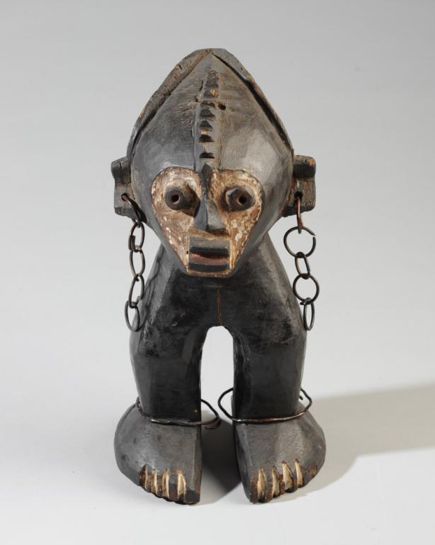Zande Magical Figure: Carved wood Mani cult type figure with black, white and red pigments, metal link chains in ears, metal ankle bracelets. Democratic Republic of Congo. Approx. 12 1/2" in height. Provenance: Estate of T