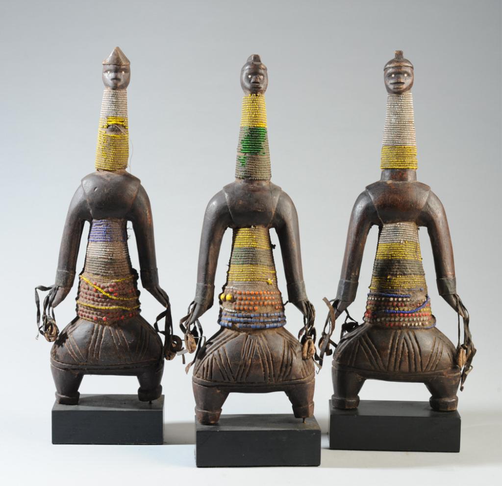 Three Namji Fertility Figures: Carved wood dolls embellished with leather fringe, beads, shells, and old British Colonial period (c.1945) 1/10 penny coins. Namji dolls are used to encourage fertiity in young women. Cameroon. On gal