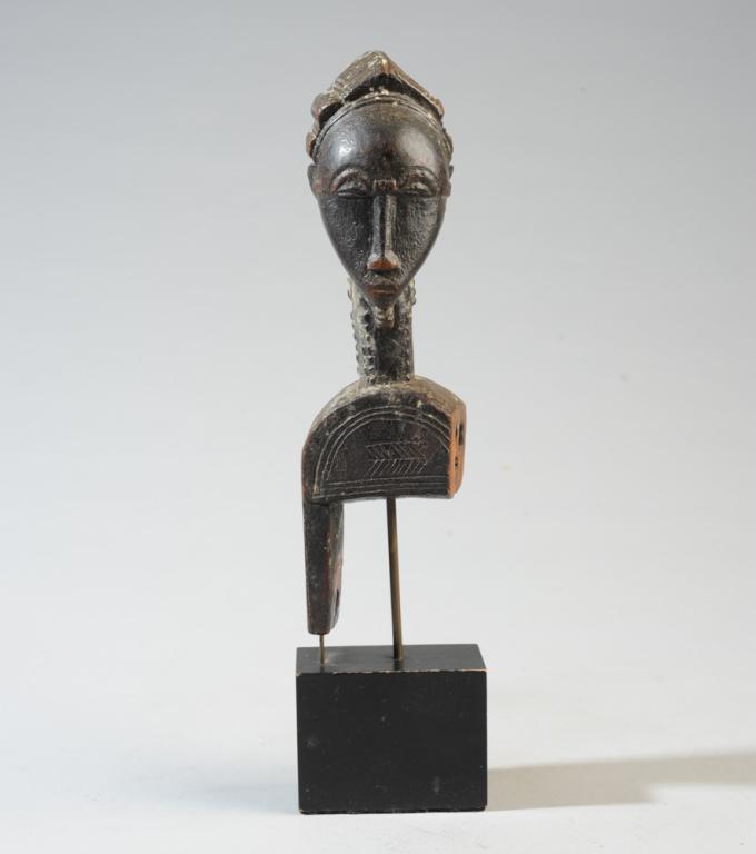 African Guro Figural Heddle Pulley: Beautifully carved heddle pulley with finial in the form of a head with ridged coiffure, heart shaped face, arched eyebrows, small chin beard, raised facial and neck scarifications. The body of the pu