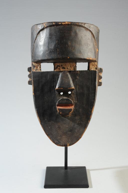Lwalwa African Mask: Black mask with white and red detail, abstracted human face, Lwalwa people, D. R. Congo. On gallery stand. Mask, approx. 12 1/2" x 8". Provenance: Estate of Thomas McNemar, (1931-2019.) McNemar lived 