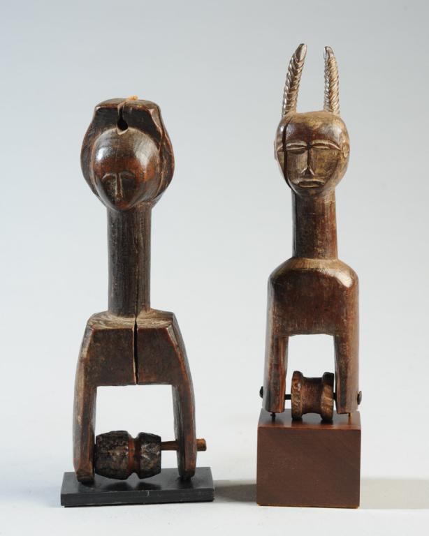 Two Figural West African Heddle Pulleys: Probably Baule people, Ivory coast. One pulley with a human head with long carefully incised horns. The other with a human face on one side and a relief carving of a lizard or crocodile on the other.