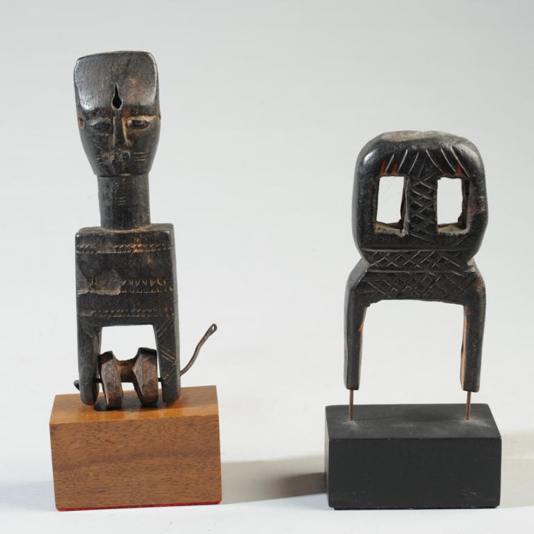 Two West African Heddle Pulleys: One of anthropomorphic form, a figure with a flattened, chisel shaped head, large eyes, cheek and neck scarification, the body of the pulley with incised decoration. The other pulley of abstract form 