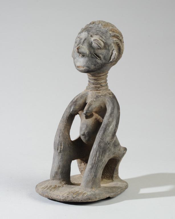Akan Terracotta Female Figure: Seated female figure with ridged coiffure, coffee bean eyes, facial scar on one cheek, slender ringed neck, prominent breasts and protruding belly. Deep grey-black surface. Ghana. Approx. 9 1/4" in he