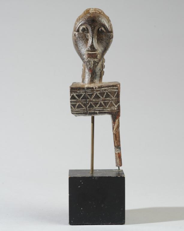 Baule Heddle Pulley: Male head with elaborate ridged coiffure, arched brows, pointed beard, long neck with relief scarification. Significant losses to lower portion. Collected prior to 1966 near Seguela, Ivory Coast. On c
