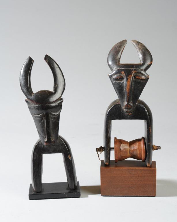 Two Zoomorphic African Heddle Pulleys: In the form of horned creatures, probably buffalo or antelope, with inward curving horns, triangular faces with rather human features, slender curved necks. The closed crescent eyes of the pulley on t