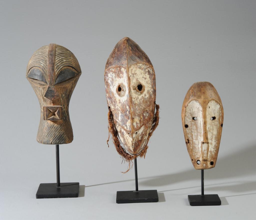 3 DR Congo Miniature Masks, Songye, Lega: The larger Lega mask with some fiber intact, white pigment, carved wood, oily patina. The smaller Lega mask with white pigment. The Songye mask with vestiges of white pigment. All on custom gallery st