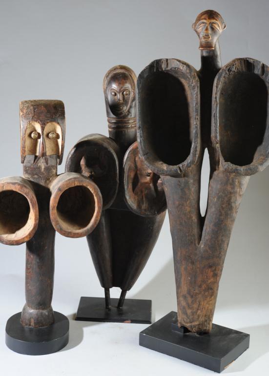 Three Blacksmith Bellows, Kwele, Fang: Three carved wooden figural bellows, Kwele and Fang people, Gabon. One retains its leather bags, the others do not. All on custom gallery stands. Approx. 35", 29", and 26" in height. Provenance: Estat