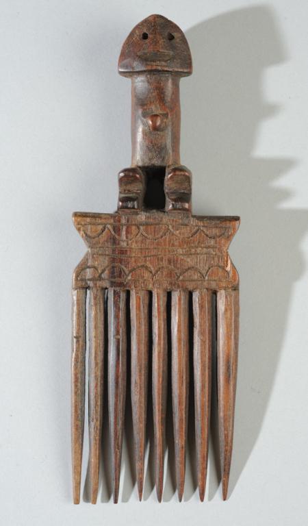 Zande African Comb: Carved wood comb topped with smiling Zande type figure. Approx. 7 1/4" L. Provenance: Estate of Thomas McNemar, (1931-2020.) McNemar lived and collected throughout Central and West Africa in the 1960s