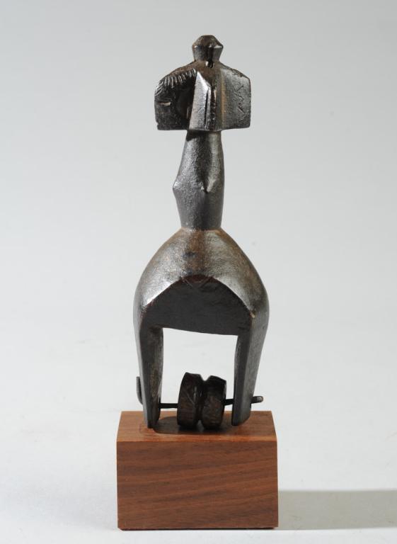 African Heddle Pulley: Of abstract form, the top with four wedge-shaped projections, one with the form of a human face, the other three with geometric incised figures, supported by a long neck with projecting points on thre