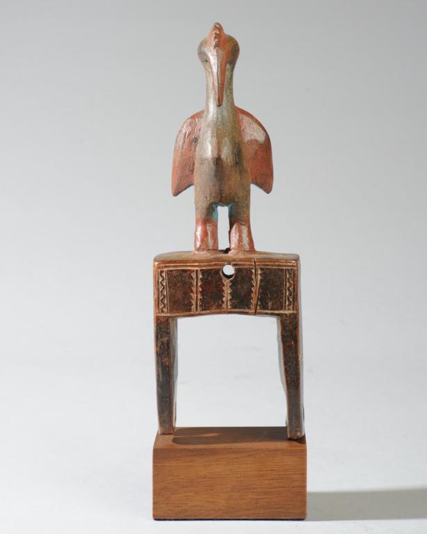 African Heddle Pulley with Bird: Heddle pulley with incised decoration topped by a a bird with a ridged crest, long downward pointing beak, wings held out at either side of a round belly and standing on two sturdy cylindrical legs. B
