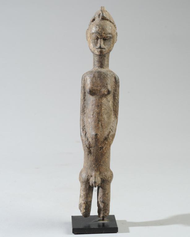 Baule Standing Male Figure Ivory Coast: Asie Usu diviner's figure, its beauty meant to lure unpredictable forest spirits close enough to consult. The carving reflects Baule ideals of human grace, with its careful coiffure, roung forehead, a