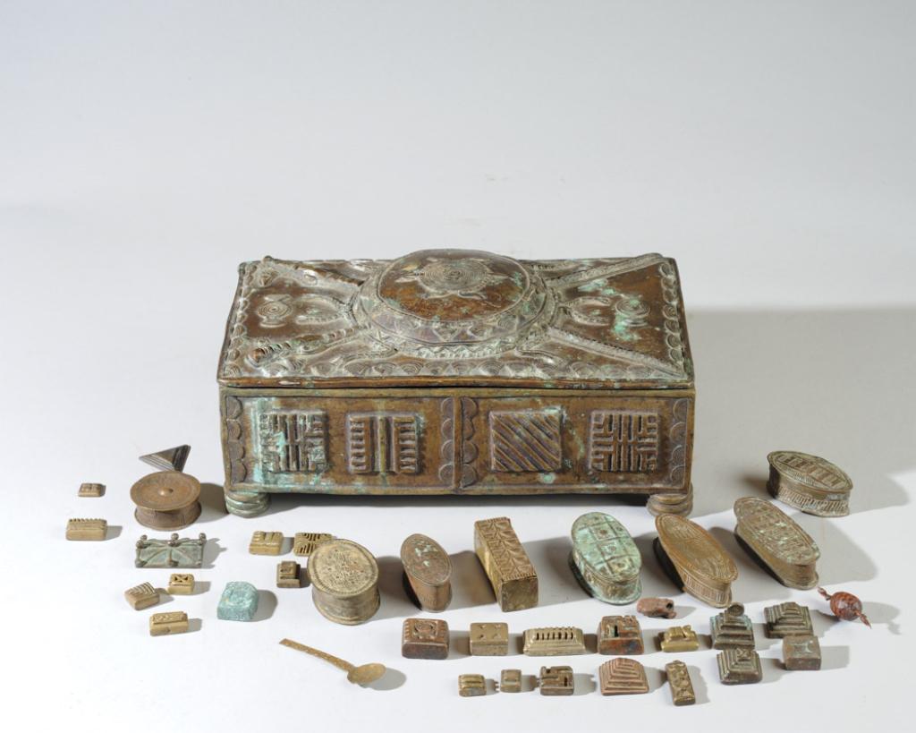 Akan Asante Gold Dust Boxes, Weights +: Cast bronze box, the top with a shield with a turtle, what appear to be crossed spears, with fish in two corners and shell-like borders, this box containing eight small brass boxes ("abamphruwa") for 