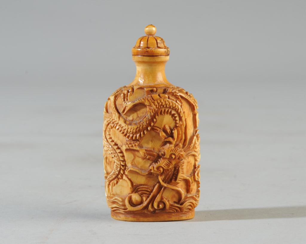 Chinese Carved Bone Dragon Snuff Bottle: With two dragons carved in high relief chasing a flaming pearl amidst clouds and ocean waves. No mark. Original lid with spoon. Approx. 3" H.