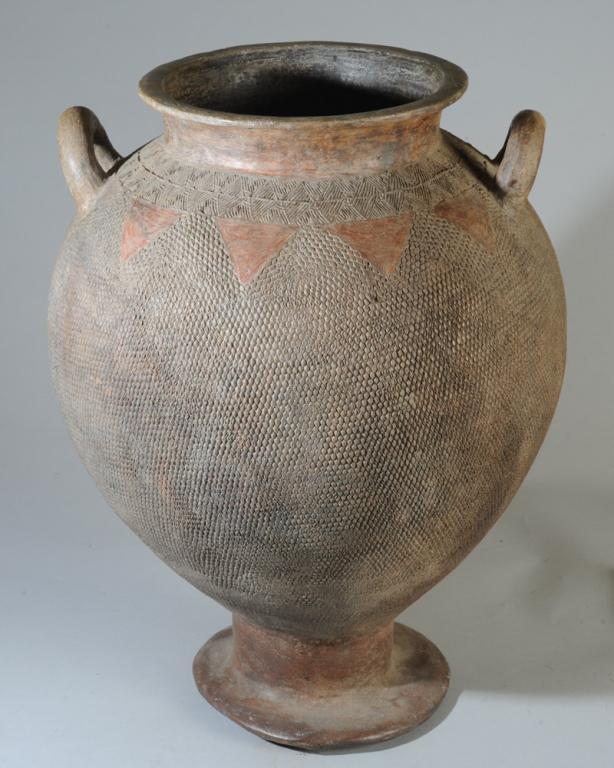 Calabar Terracotta Jar, Nigeria: Elegant amphora on pedestal foot, having wide mouth with everted rim, dual handles, impressed textural surface decoration. Minor old chips. Approx. 21" H. Provenance: Estate of Thomas McNemar, (1931-2