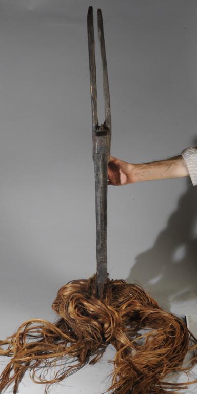 Bambara Chiwara Headdress: Large headdress in the form of a highly abstract antelope. Long raffia and rope collar hangs like a curtain below. Old repairs; appears to have signs of age and use. Mali. Headdress (wooden part only)