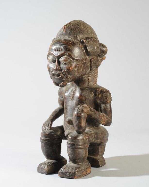 Seated Baule Male Figure: Male figure with elaborately arranged hair, relief carved scarification to face and body, arched brows over coffee bean eyes, short, trim beard, seated on a prestige stool, right hand resting on right
