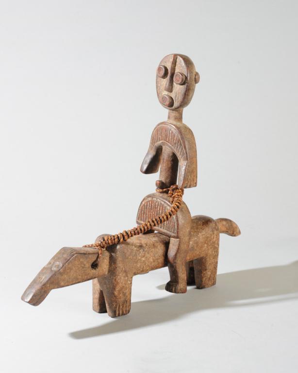 Igbo Equestrian Figure: Human figure, flattened and with simplified, abstract features, astride a short-legged horse, the horse and rider tethered together with twisted rope. Igbo people, Nigeria. Approx. 13" H, 15" L.Proven
