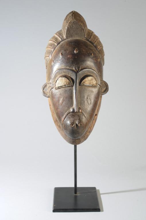 Fine Baule Mblo Portrait Mask: Baule helmet mask as used in the Mblo performances, with the refined features expressing Baule ideals of classic human beauty; elaborately arranged hair, rounded forehead, arched brows over half close