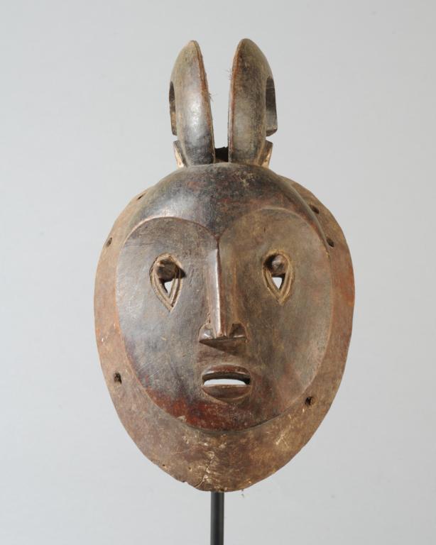 Baule Mask: Two curved horns flanked by tiny pointed ears above a heart shaped face, the inverted teardrop eyes like those in Goli klpeklpe masks, but with a delicate, human nose and small pouting lips. On custom