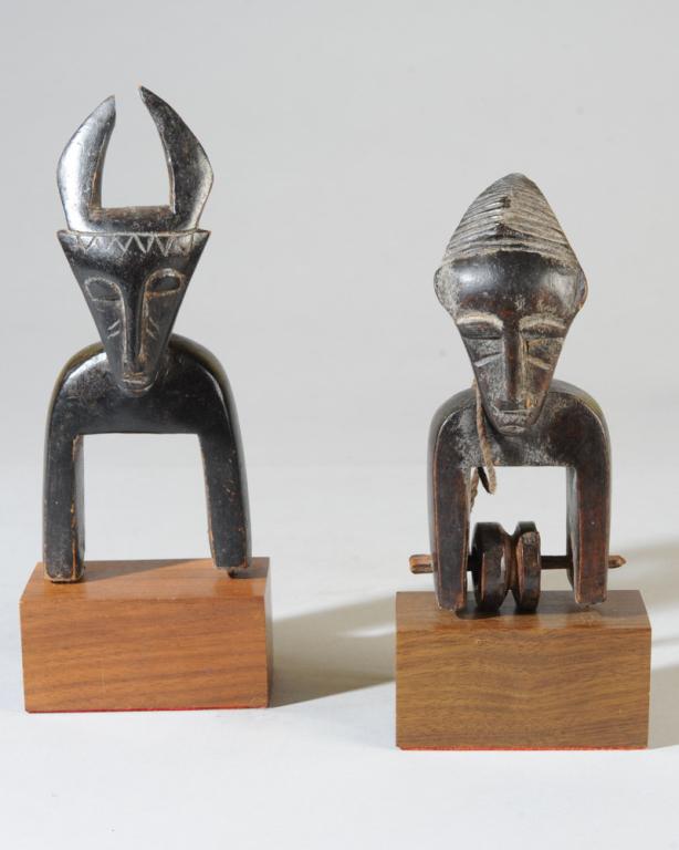 Two Jimini Heddle Pulleys, Ivory Coast: One with buffalo head finial, the other with backswept horn-like coiffure, both with triangular faces, long curved necks. On custom gallery stands. Approx. 6" and 7 1/8" in height. Provenance: Estate