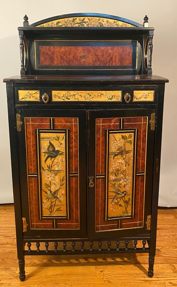 Aesthetic Period Hand Painted Cabinet: Circa 1870 - 80, American, hand painted and gilt incised, with open shelf and gallery on turned ebonized supports, drawer over doors with bird and floral motif, spool turned apron over ring turned fee